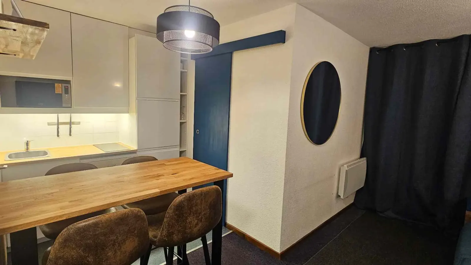 Coin repas avec table en bois massif et cuisine ouverte équipée