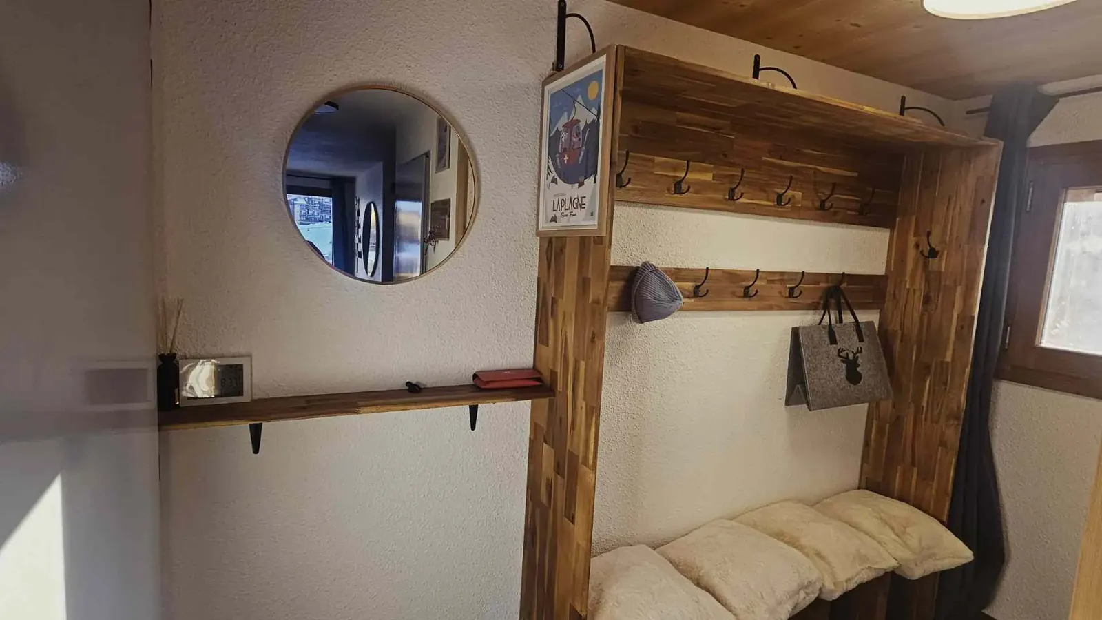 Entrée avec meuble vestiaire en bois, crochets multiples et miroir rond