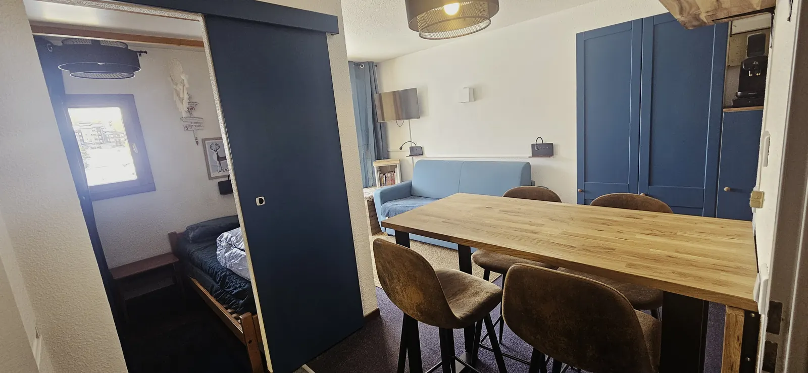 Vue d'ensemble depuis la cuisine sur le coin repas, le salon et la chambre ouverte